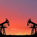 Oil pumps silhouetted against colorful sky background