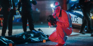 Forensic investigator examines crime scene at night.