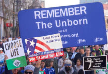 Pro-life marchers holding various anti-abortion signs.