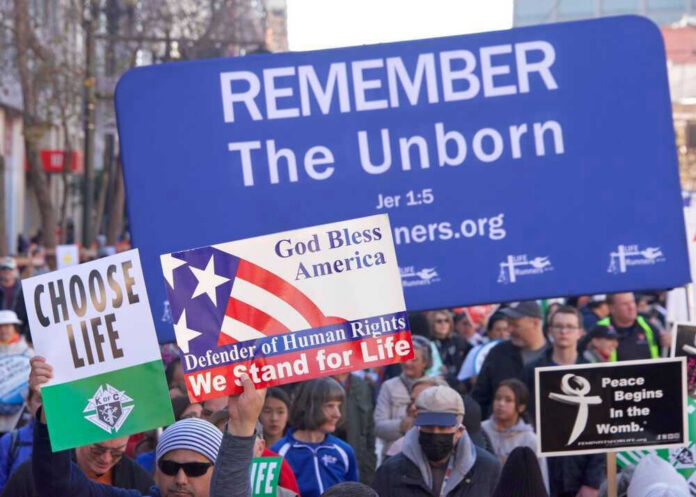 Pro-life marchers holding various anti-abortion signs.