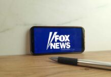 Smartphone displaying the Fox News logo on a wooden surface