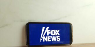 Smartphone displaying the Fox News logo on a wooden surface