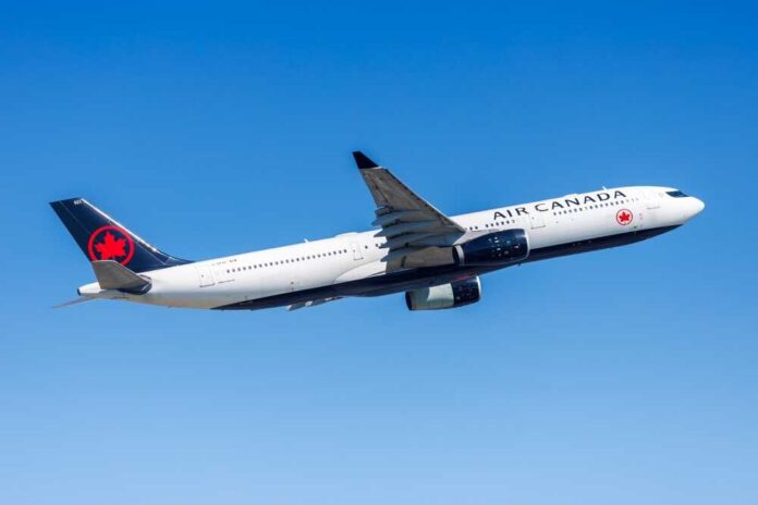 shutterstock_2469416327.jpg Air Canada airplane flying against a clear blue sky