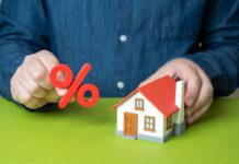 Person holding a percentage symbol above a model house