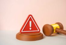 A red warning sign next to a legal gavel on a light background