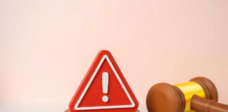 A red warning sign next to a legal gavel on a light background