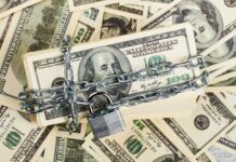 A stack of hundred dollar bills secured with a chain and padlock