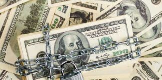 A stack of hundred dollar bills secured with a chain and padlock