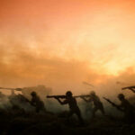 Silhouettes of soldiers advancing at sunset.