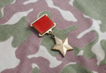 A military medal featuring a red ribbon and a star on a camouflage fabric