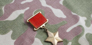 A military medal featuring a red ribbon and a star on a camouflage fabric