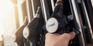 A hand holding a diesel fuel nozzle at a gas station