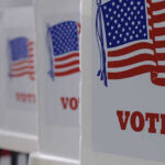 Voting booths with American flags and VOTE signs.