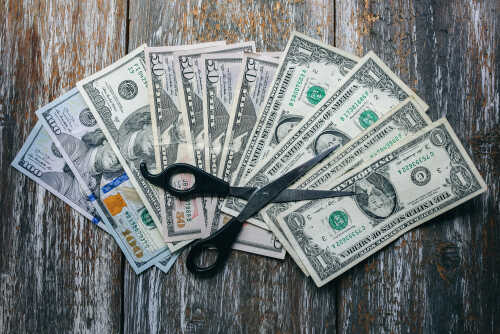 Scissors placed on a spread of various U.S. dollar bills