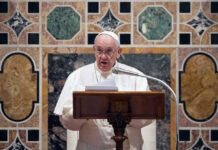 Pope Francis speaking at a podium.