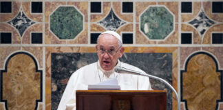 Pope Francis speaking at a podium.