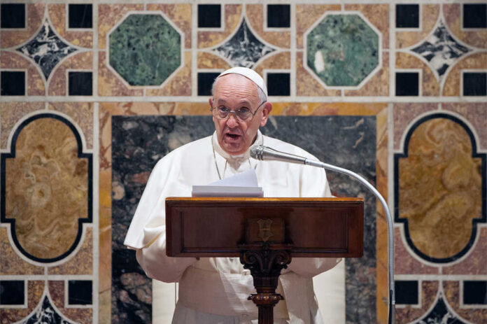 Pope Francis speaking at a podium.