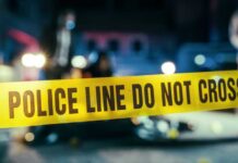 Criminal Approved for Citizenship — Then MURDERED DHS Worker Police line caution tape at a crime scene with blurred figures in the background