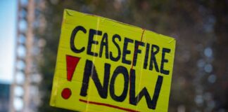 Bright yellow protest sign reading 'CEASEFIRE NOW'
