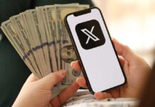 Person holding a smartphone displaying a logo with cash in the other hand