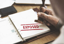 A hand stamping the word 'EXPOSED' on a document