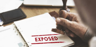 A hand stamping the word 'EXPOSED' on a document
