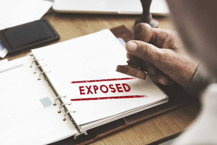 A hand stamping the word 'EXPOSED' on a document