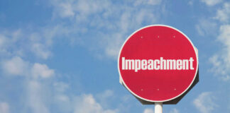 Red sign with the word Impeachment against sky