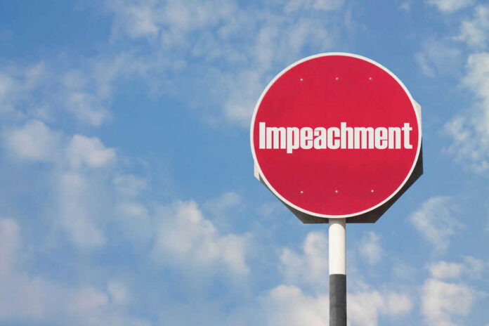 Red sign with the word Impeachment against sky