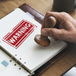 A hand applying a warning stamp on a document