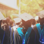 Graduates wearing caps and gowns in ceremonial procession.