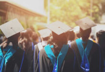Graduates wearing caps and gowns in ceremonial procession.