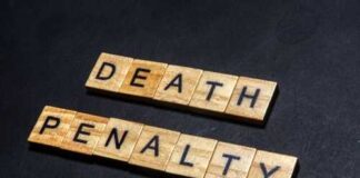 Wooden letter tiles spelling DEATH PENALTY on a dark background