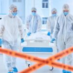 Healthcare workers in protective gear transporting a patient in a hospital