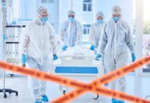 Healthcare workers in protective gear transporting a patient in a hospital