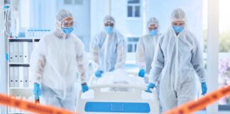Healthcare workers in protective gear transporting a patient in a hospital
