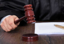 Judges hand holding gavel next to documents.