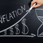 Chalkboard drawing of inflation with rising dollar symbols.