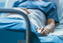 A patient lying in a hospital bed with a monitoring device in hand