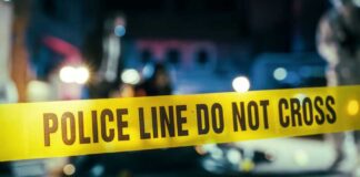 Horrific Bloodshed: One Afternoon, Seven Gone Police line caution tape at a crime scene with blurred figures in the background