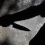 Shadow of a hand holding a knife on a textured surface