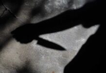 Shadow of a hand holding a knife on a textured surface