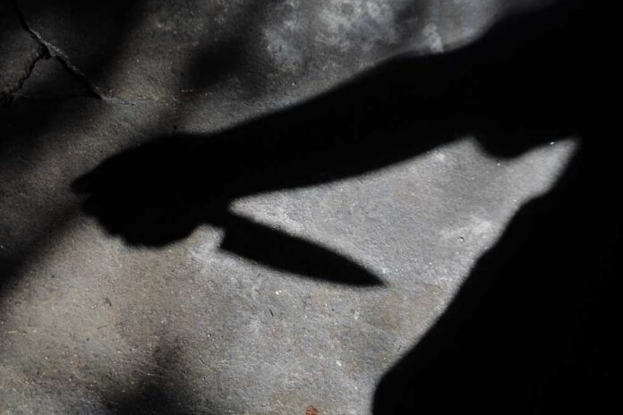 Shadow of a hand holding a knife on a textured surface