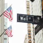 Wall Street sign and traffic light in a city street with American flags