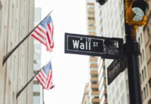 Wall Street sign and traffic light in a city street with American flags
