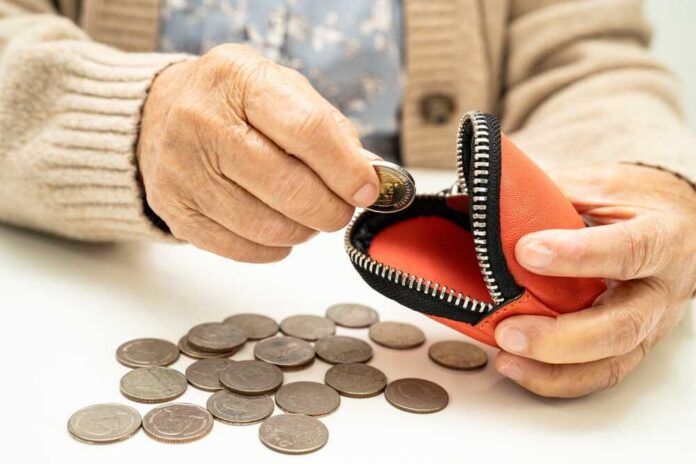 Elderly person placing a coin into a red coin purse