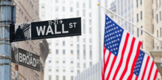 Street signs for Wall Street and Broad Street with American flags