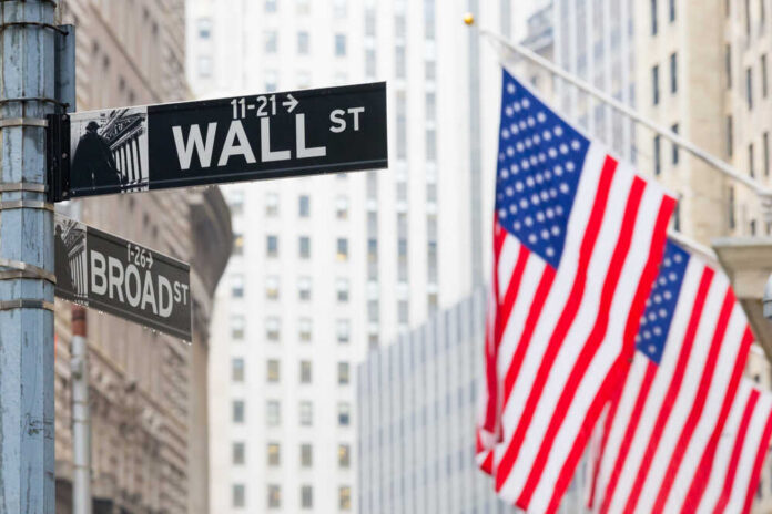 Street signs for Wall Street and Broad Street with American flags