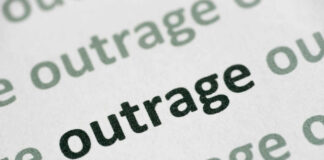 Close-up of the word 'outrage' printed in bold on paper