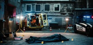 Police investigation at a crime scene with a covered body and evidence markers